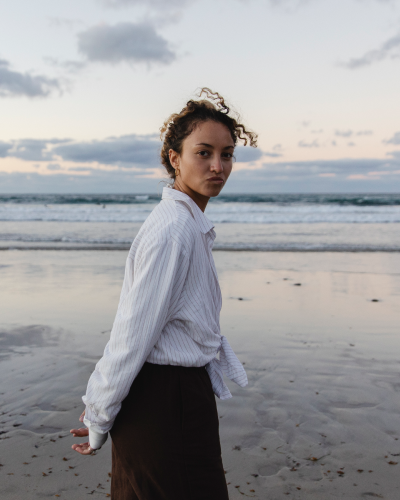 Frau lachend an einem Steinstrand